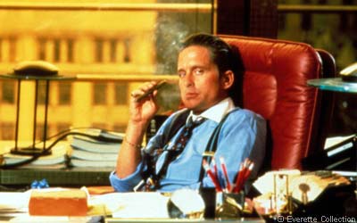 Wall Street (1987) filminden bir sahne: Gordon Gekko ofisindeki deri koltuğunda puro içiyor